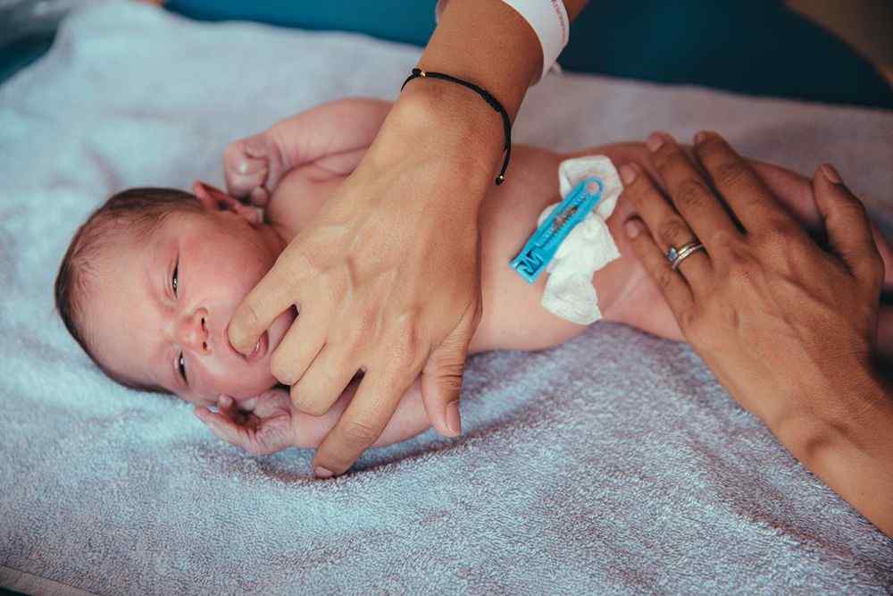 Battaniye üzerinde yatan yenidoğan bebeği esenler sünnet kliniği personeli eli ile tutuyor; göbek kordonunda klempli bağ bulunuyor