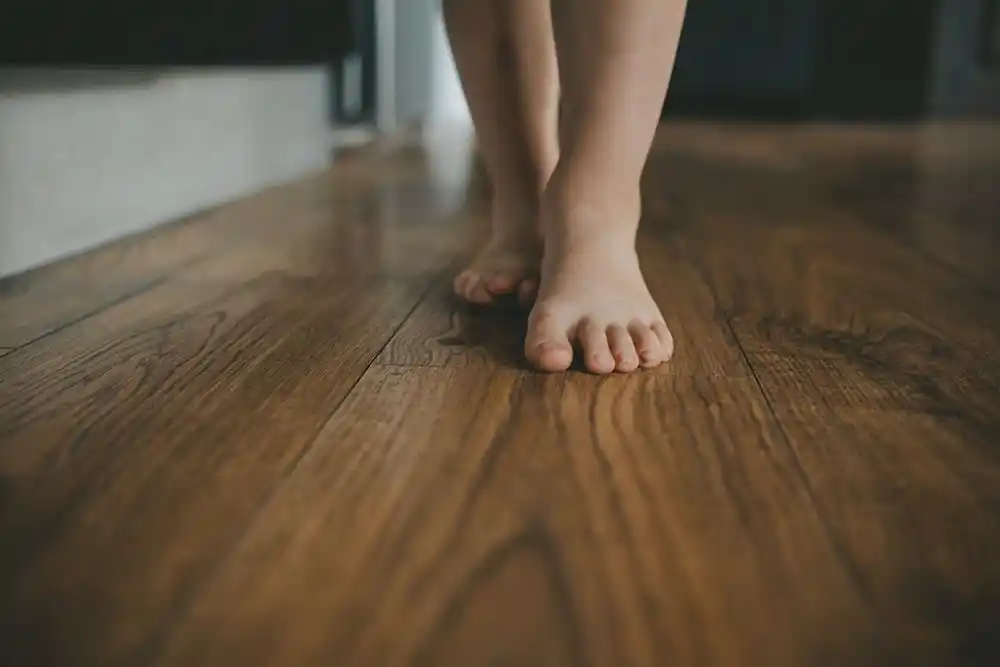 Ahşap zeminde çıplak ayakla yürüyen kişinin ayakları